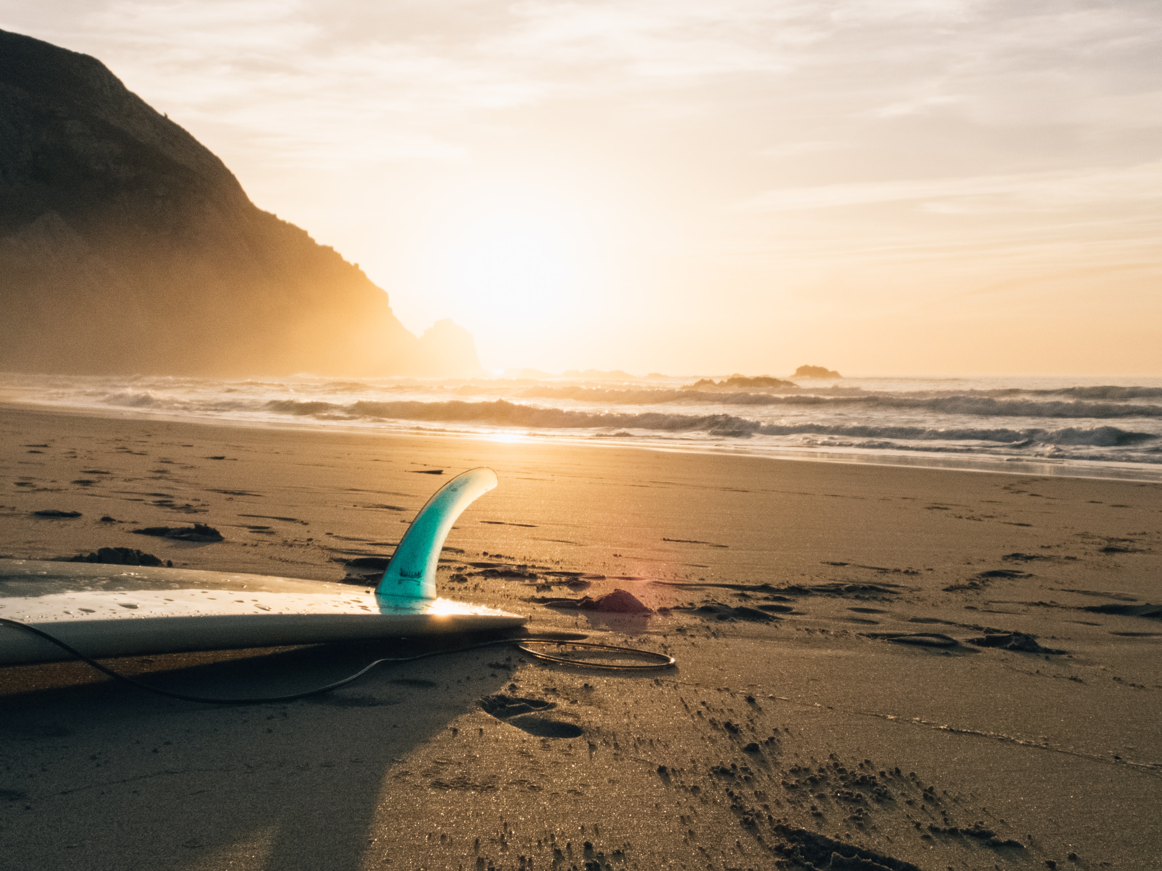 surf board on beach at sunset