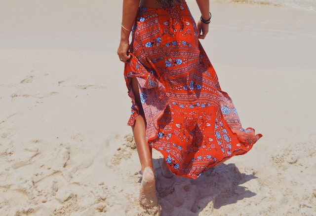 lady with red dress walking on beach