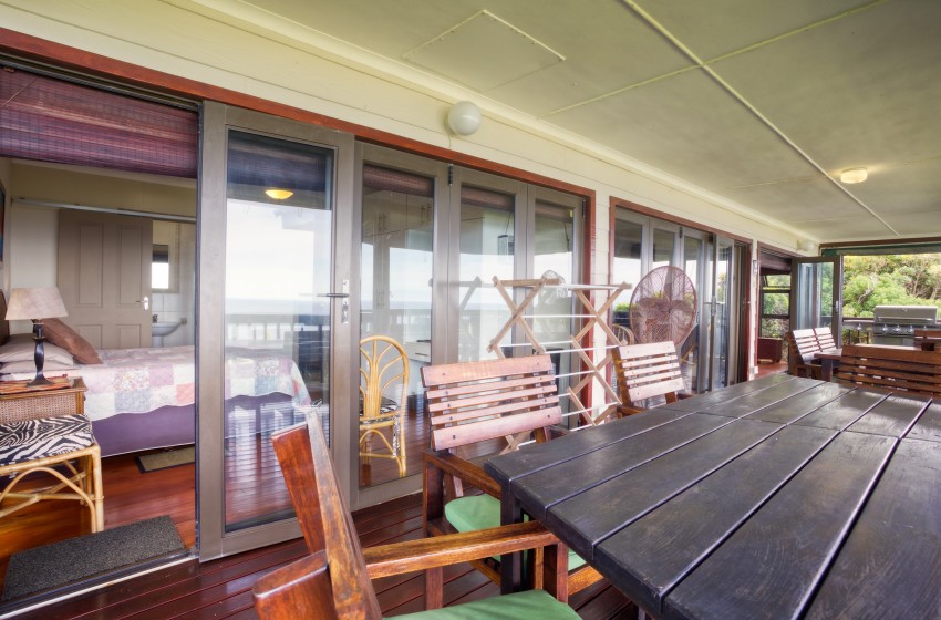 Deck with dining table and bedroom view at Campismo Ninho 23 in Ponta Malongane